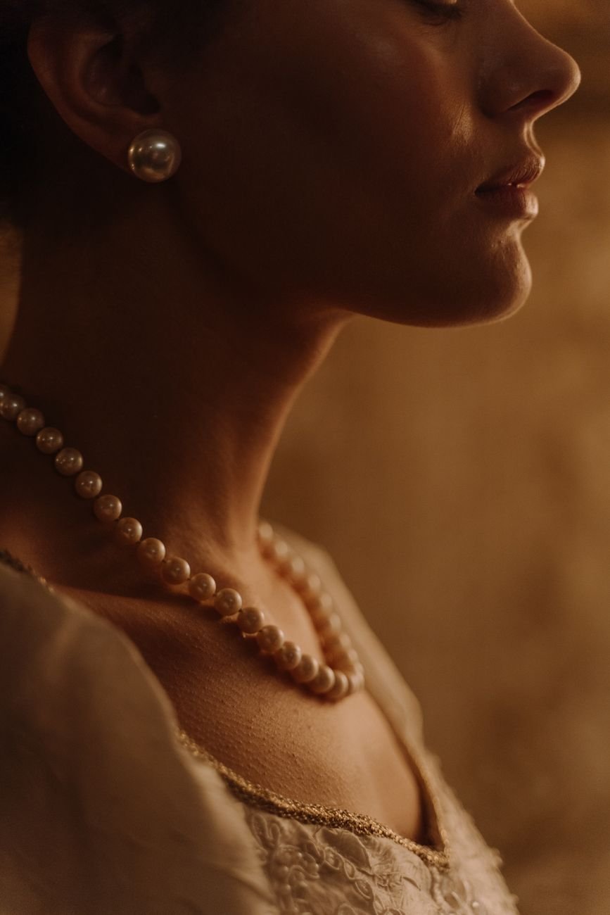 Close-up portrait of a woman wearing elegant pearl jewelry set in a warm ambiance.