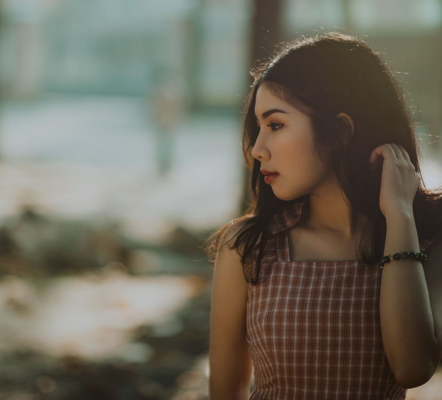 A serene portrait of a woman in a checkered dress enjoying the warm summer outdoors.